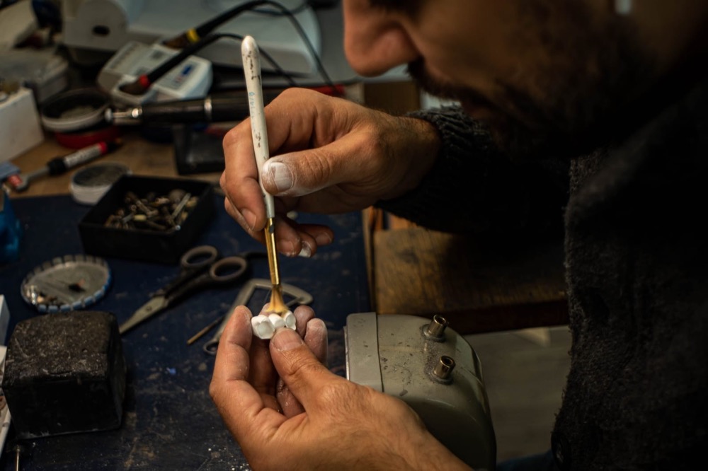 Zahntechniker modelliert Zahnersatz von Hand
